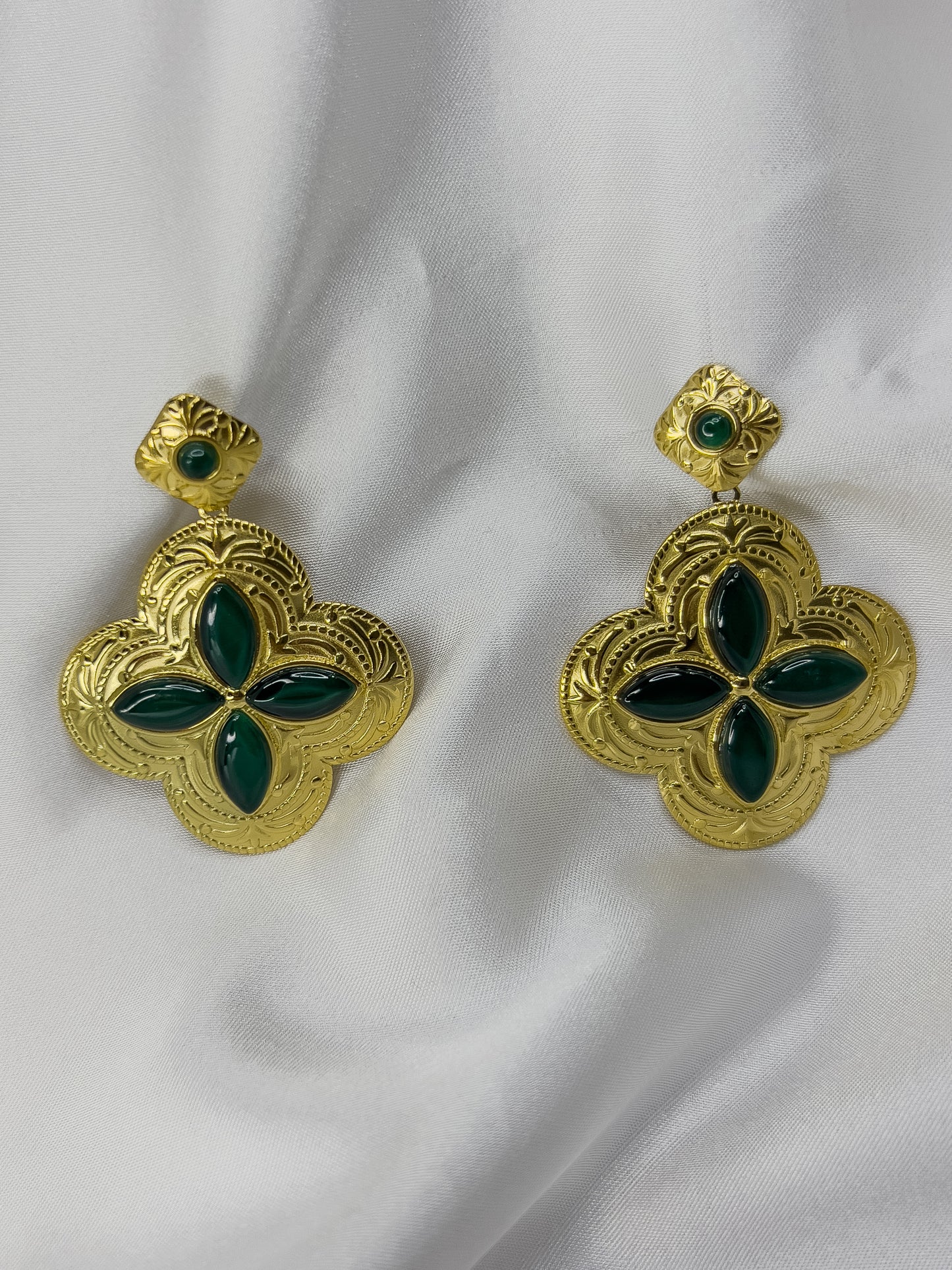 aretes dorados en forma de pétalo con acabados en verde esmeralda.